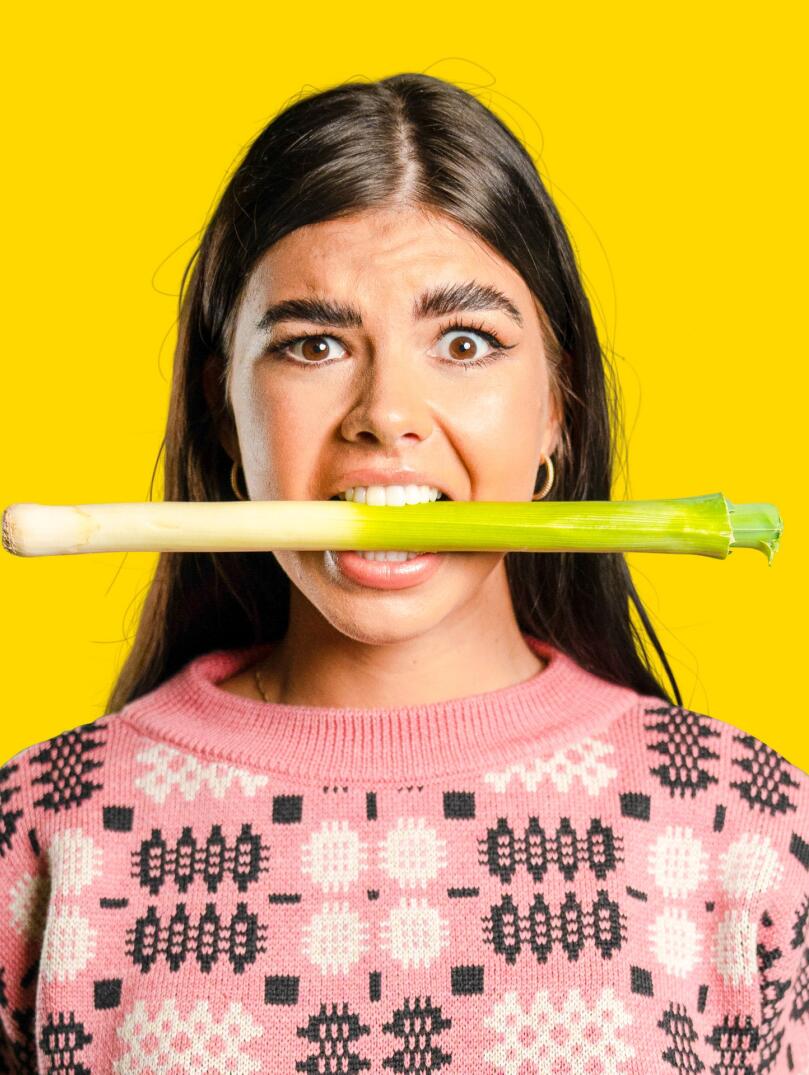 A girl holding a leek in her mouth