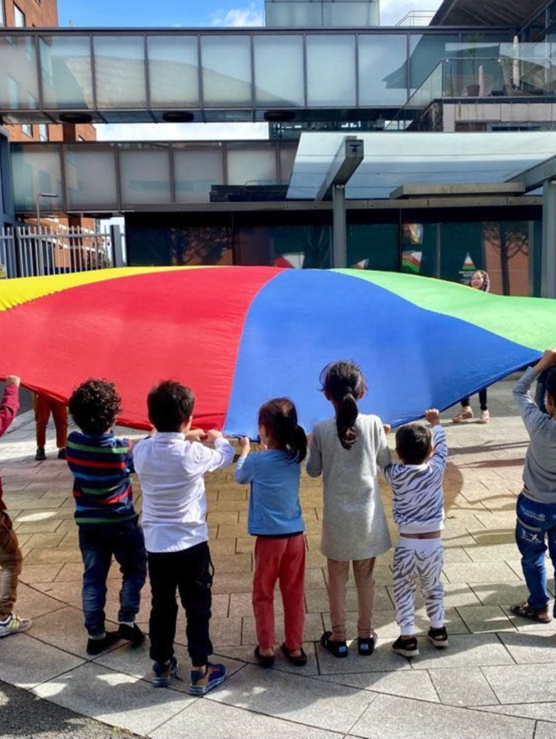 A group of children playing with a parachute.
