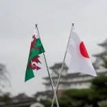 A Welsh flag and a Japanese flag shown in the foreground, with a Japanese castle in the background