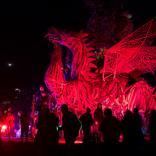 Toma nocturna de la escultura gigante del dragón rojo con gente parada mirando