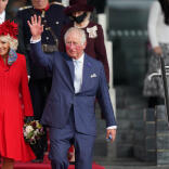 Le roi Charles III accompagné de la reine consort, descendent quelques marches et saluent la foule.