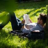A person lying on the grass reading a book.