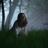 Una persona de rodillas en el césped en un bosque oscuro y espeluznante por la noche