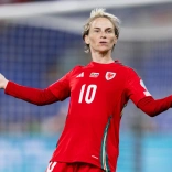 Dressed in her number 10 red football jersey, Fishlock stands with her arms out to her sides with a questioning look on her face
